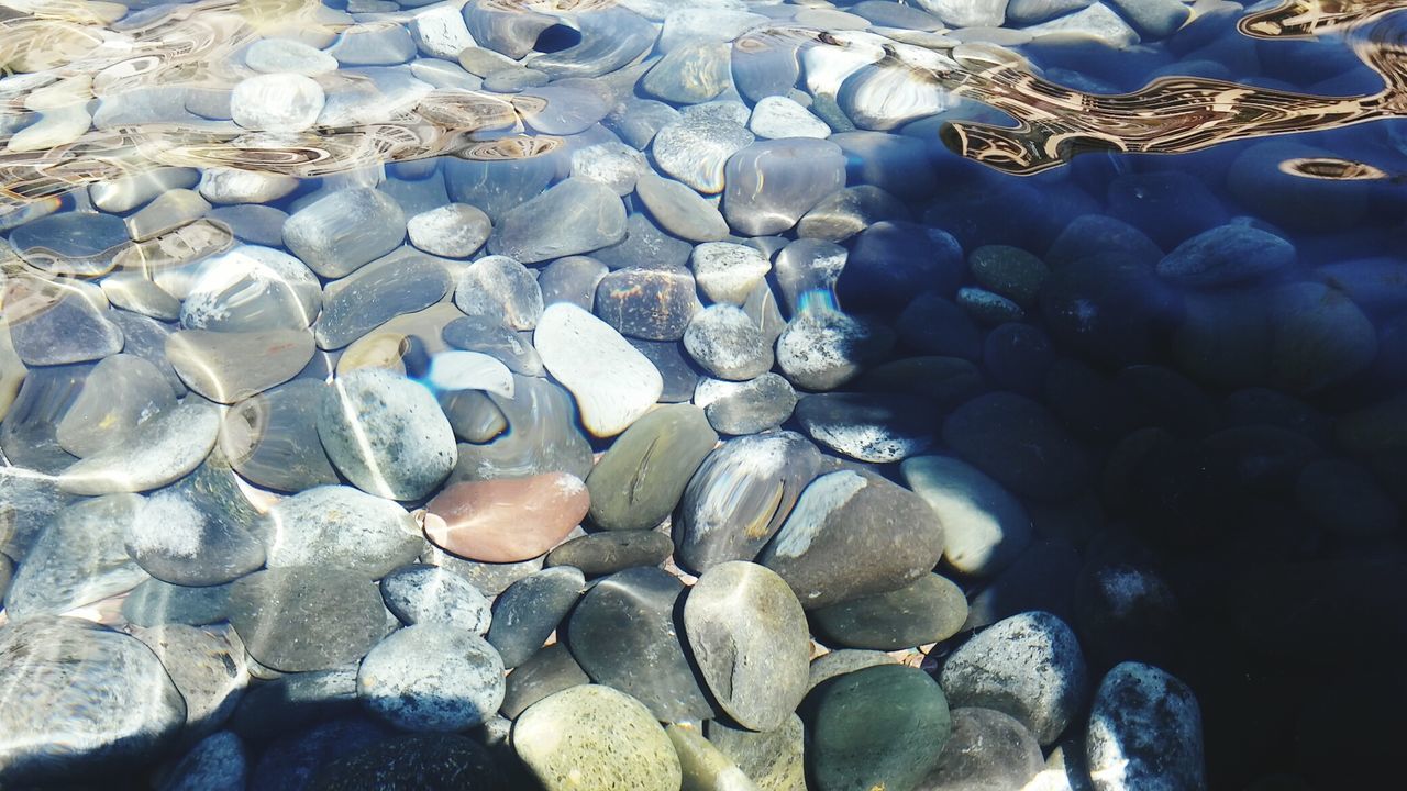HIGH ANGLE VIEW OF PEBBLES ON BEACH