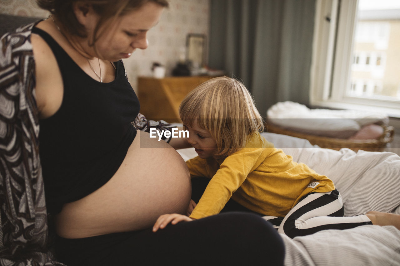 Girl talking to pregnant mother's belly