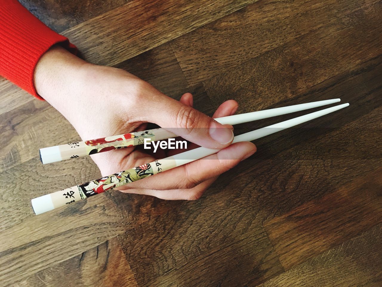 Cropped hands holding chopsticks at table