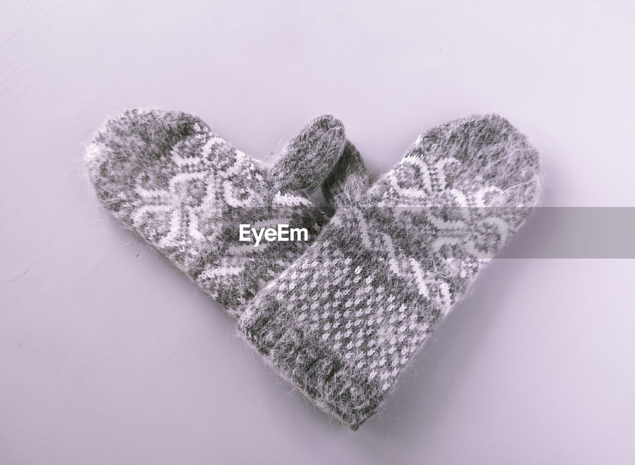 High angle view of heart shape made with gloves over gray background