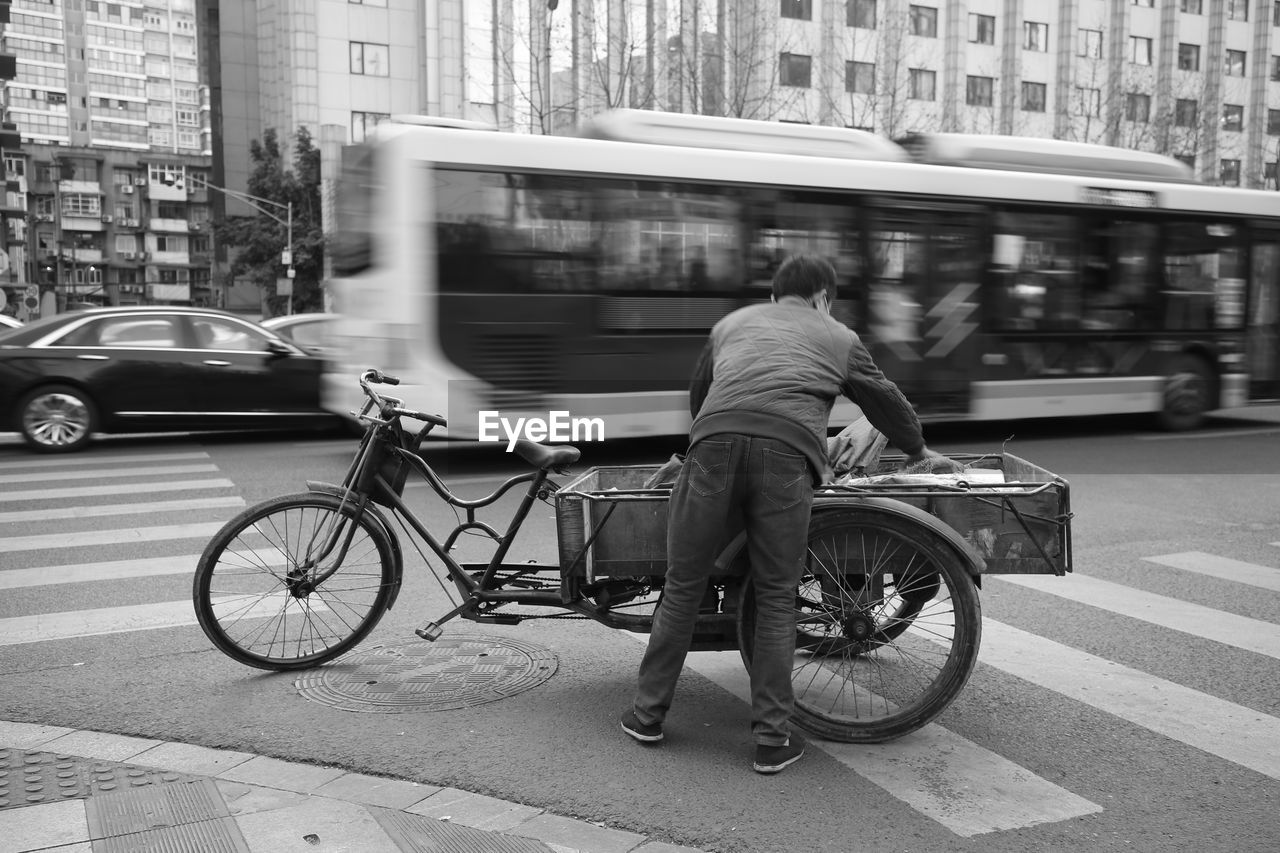 Rear view of man riding motor scooter on street