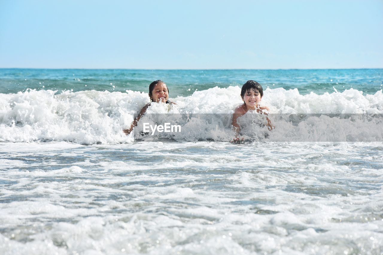 MAN SPLASHING WATER IN SEA AGAINST SKY