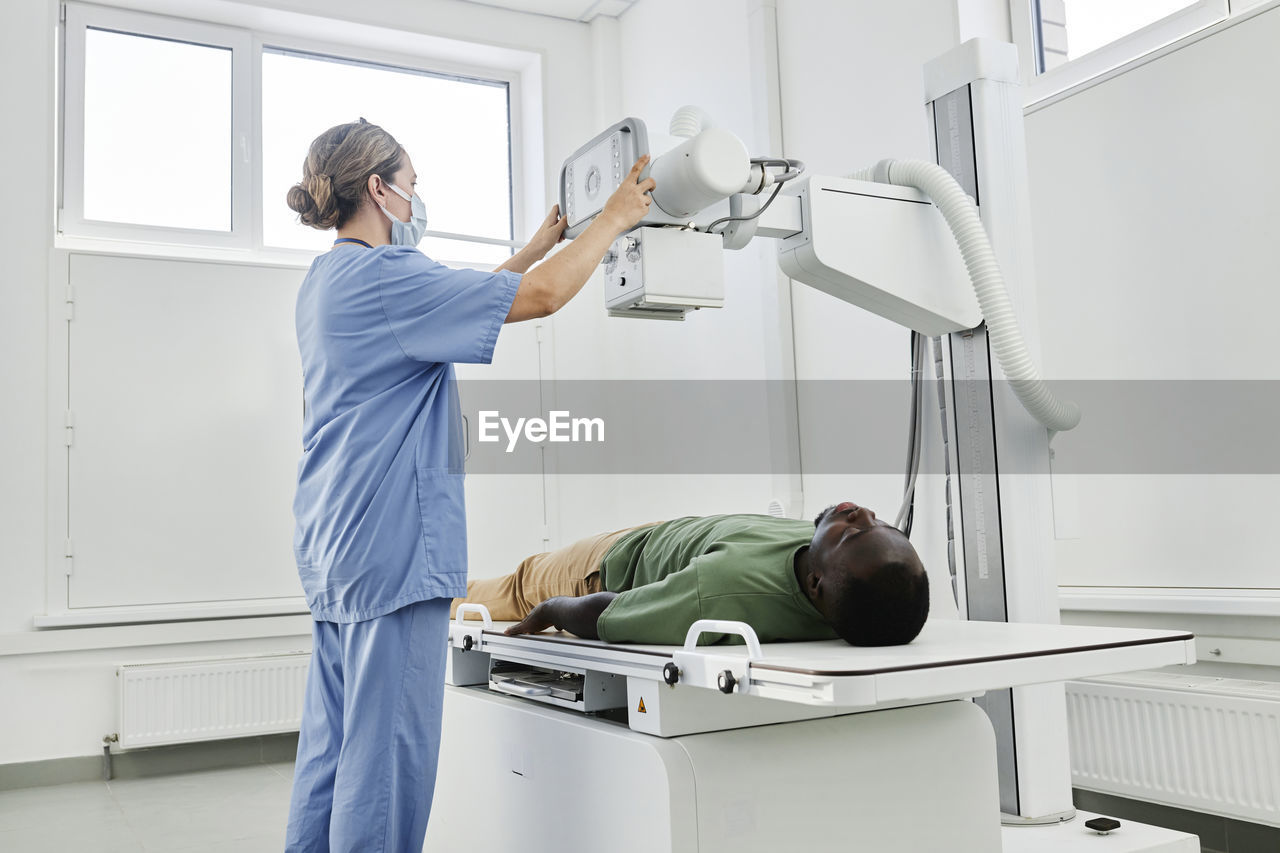 Nurse adjusting x-ray machine for patient in clinic