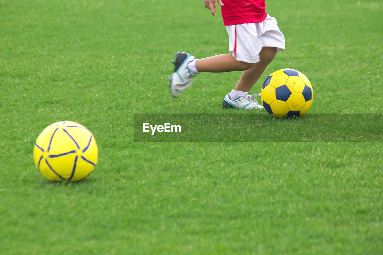 Low section of boy playing soccer on field