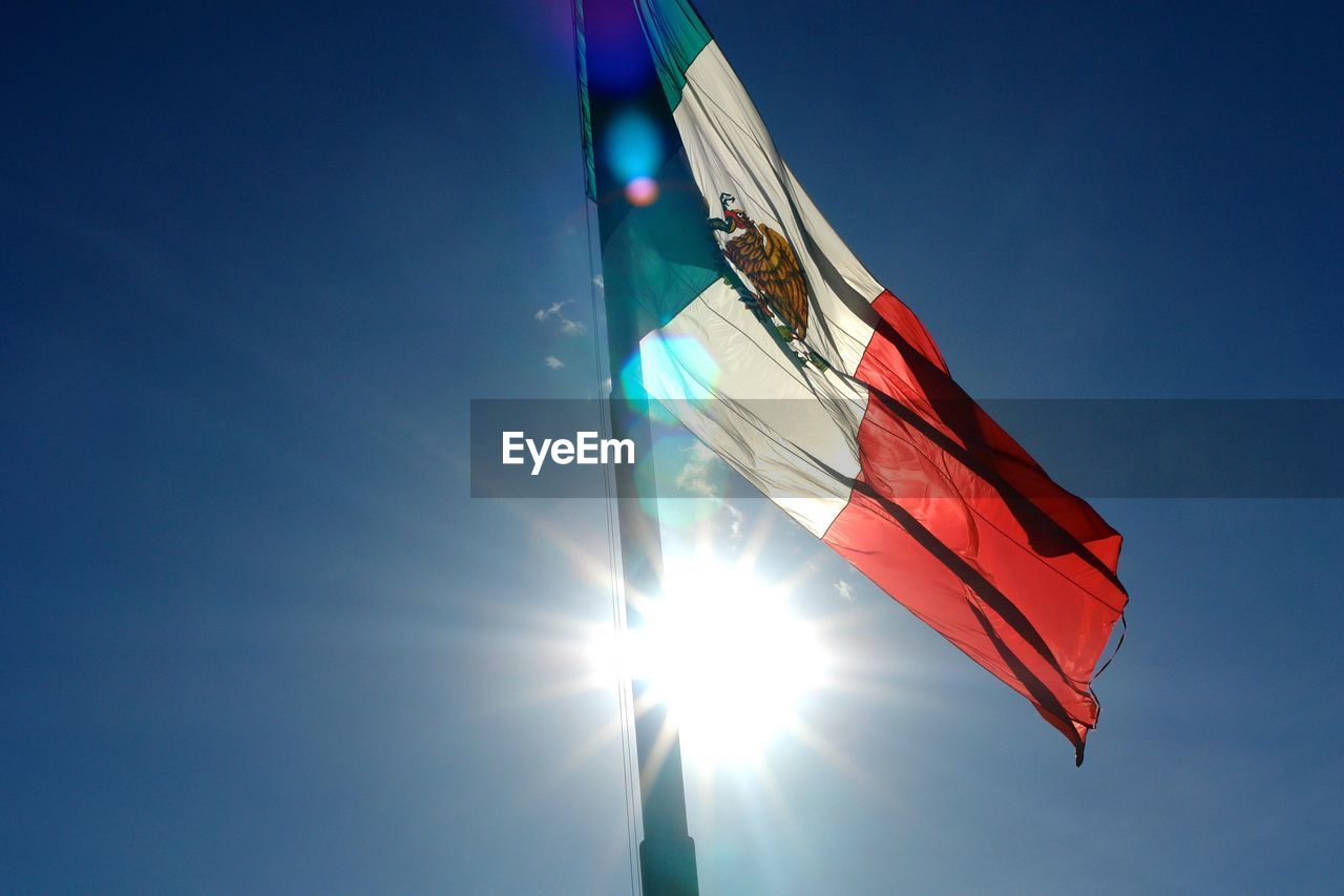 Low angle view of mexican flag against blue sky