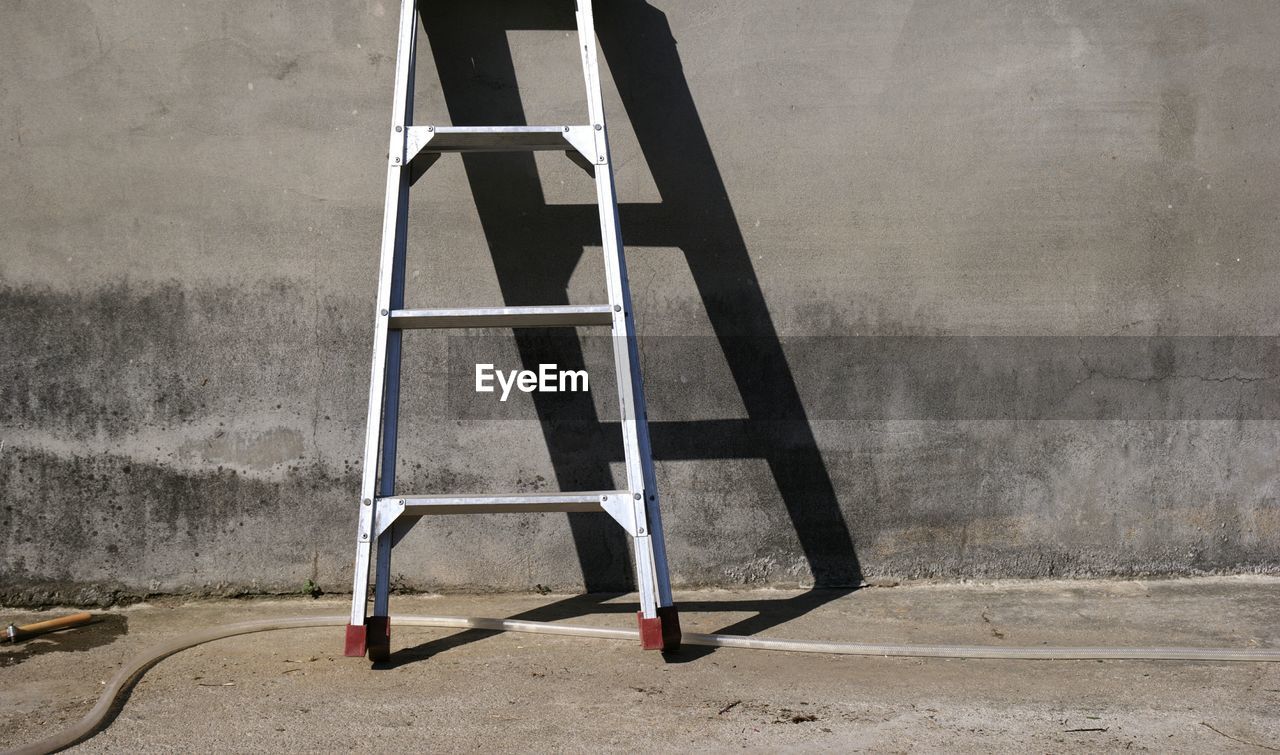 Ladder leaning against grey wall