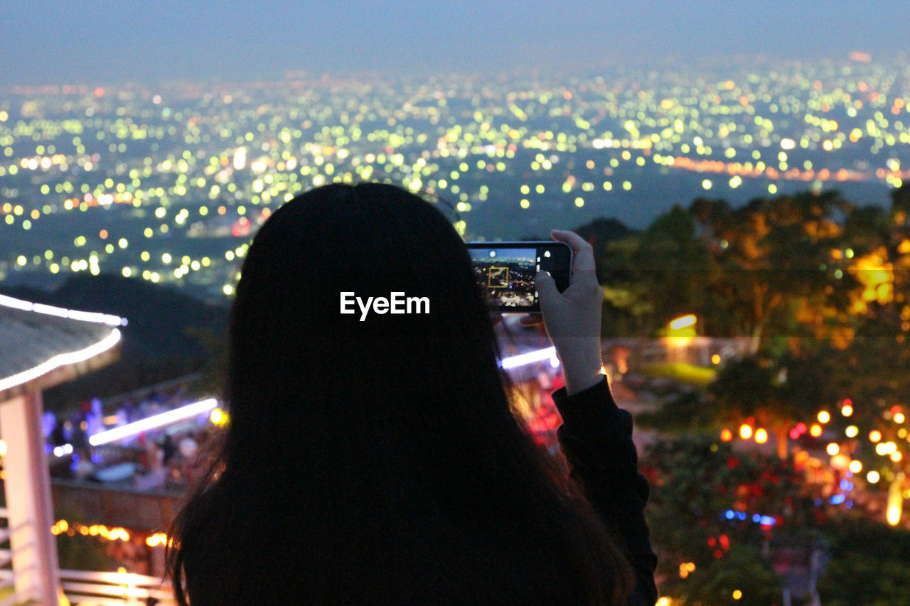 REAR VIEW OF WOMAN PHOTOGRAPHING IN CITY