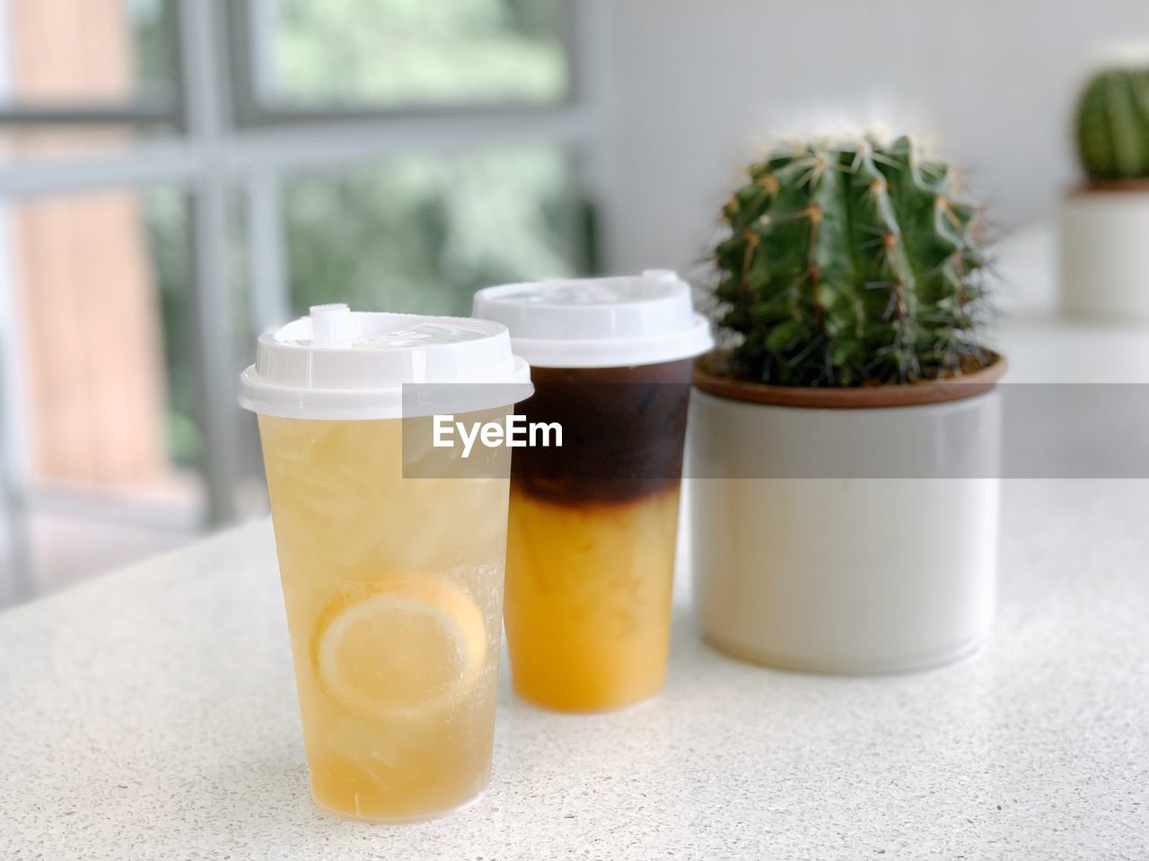 Close-up of lemon tea and orange coffee in glass on table