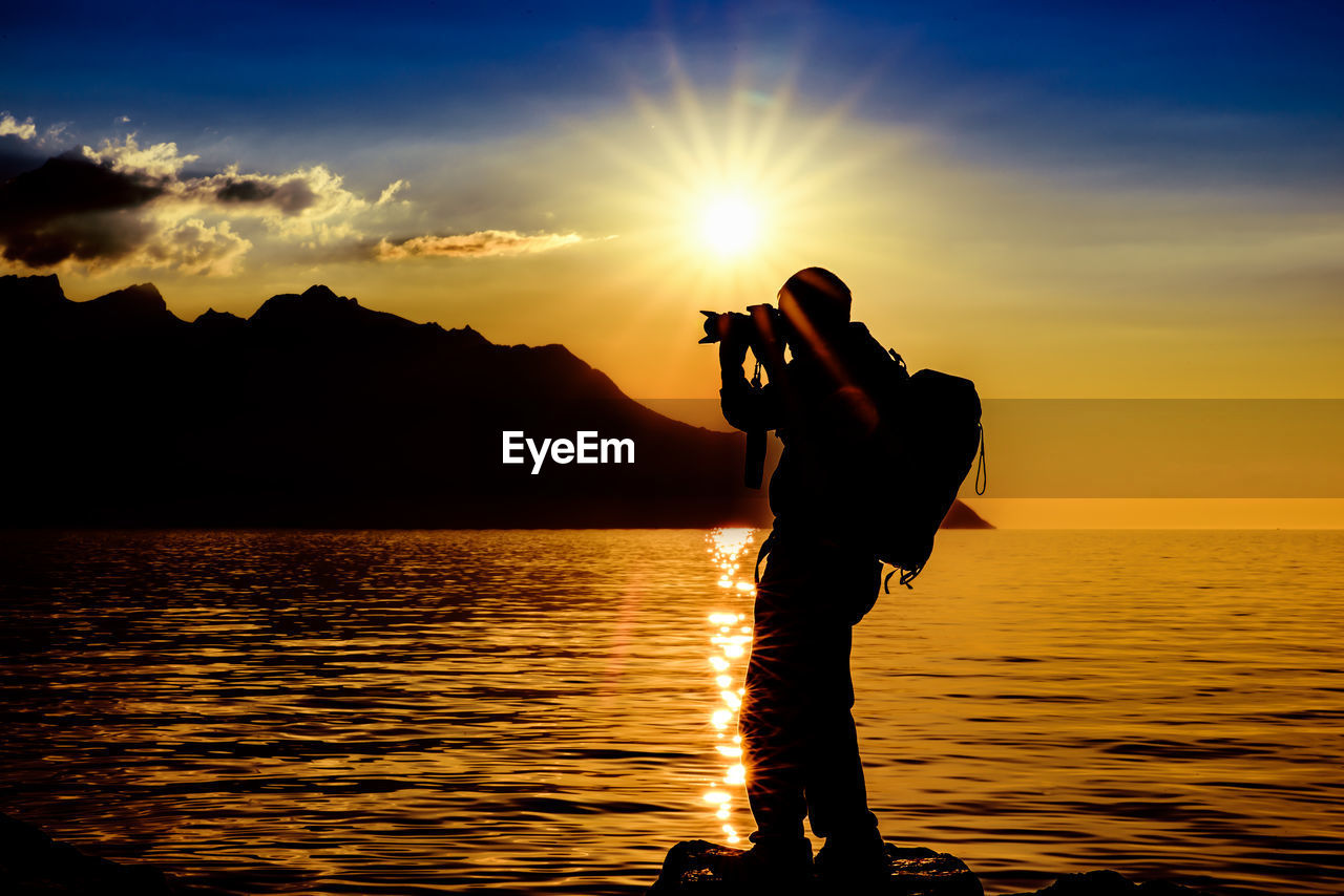 Silhouette of man taking photographs on beach