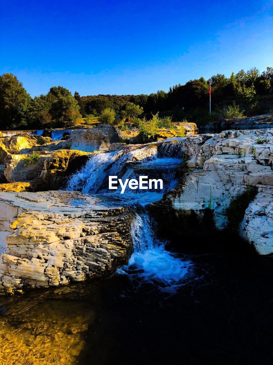 SCENIC VIEW OF WATERFALL AGAINST SKY