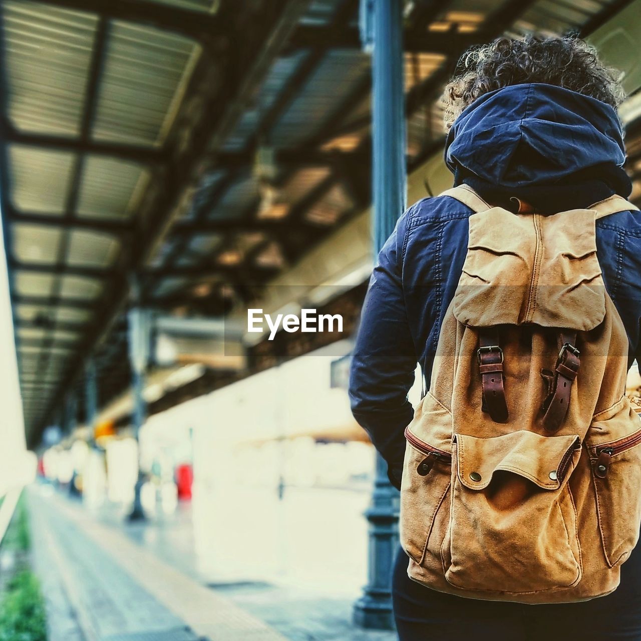 Rear view of woman with backpack standing at railroad station