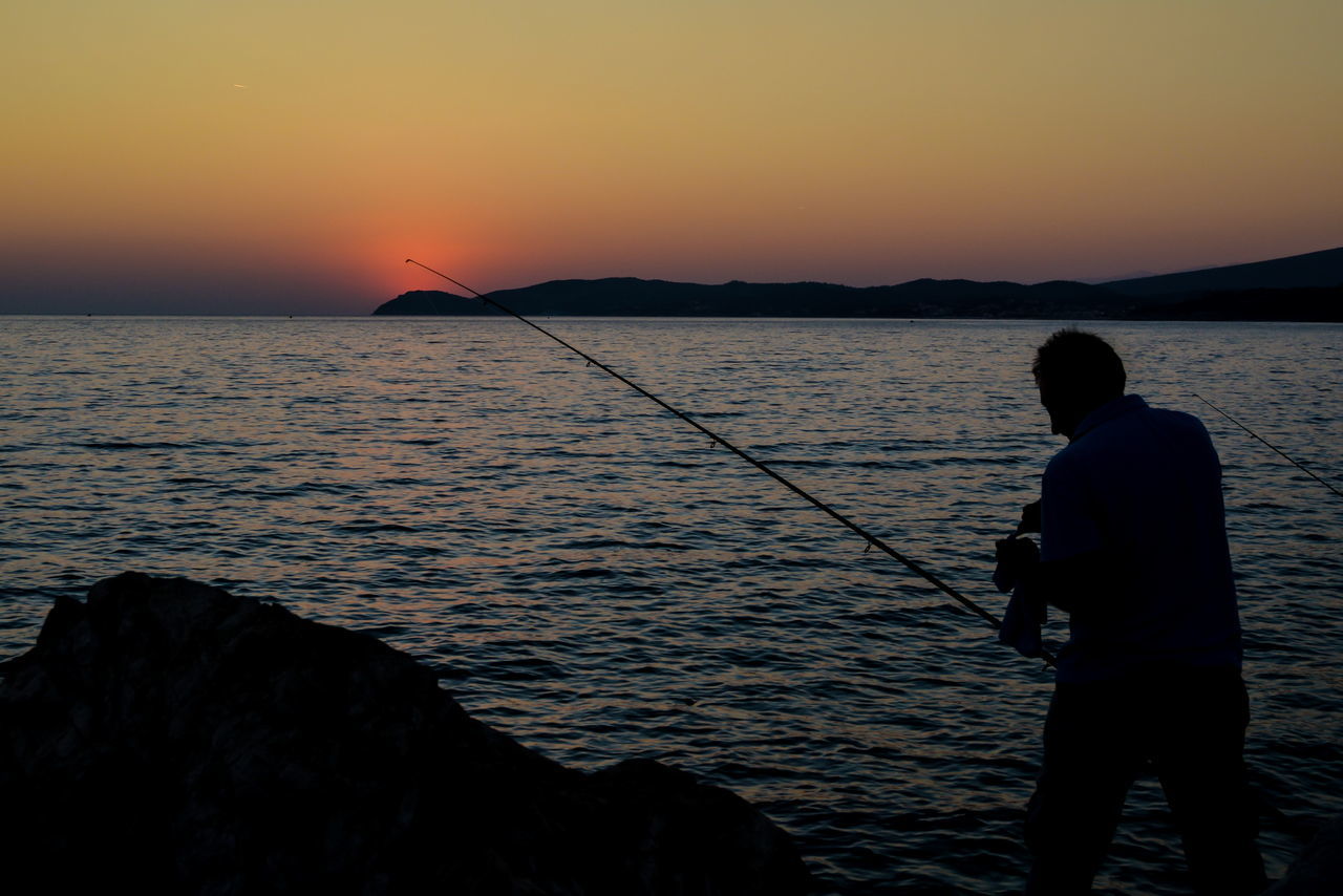 REAR VIEW OF SILHOUETTE MAN FISHING IN SEA