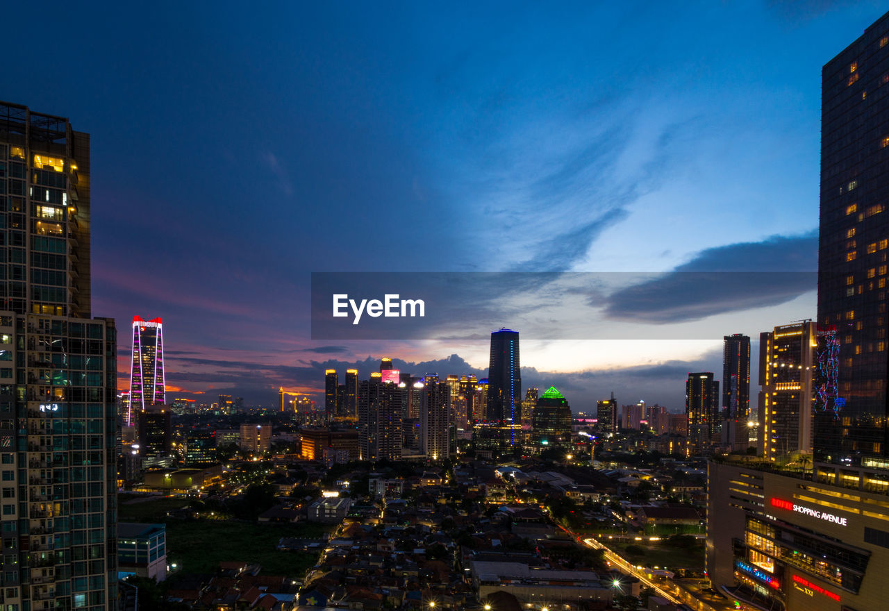 ILLUMINATED MODERN BUILDINGS IN CITY AGAINST SKY