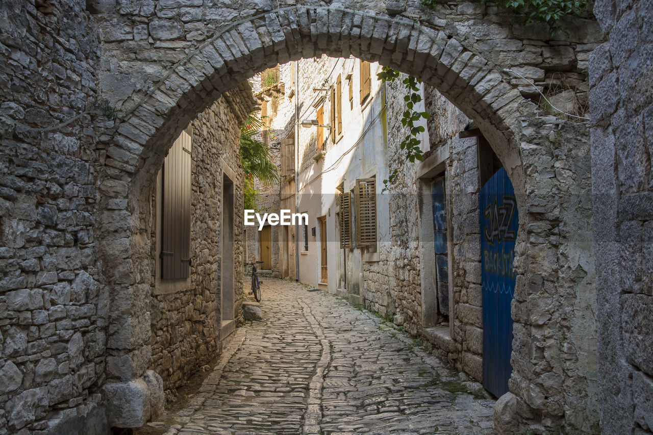 View of old narrow cobblestone street with arc and buildings in ancient town of bale istria, croatia