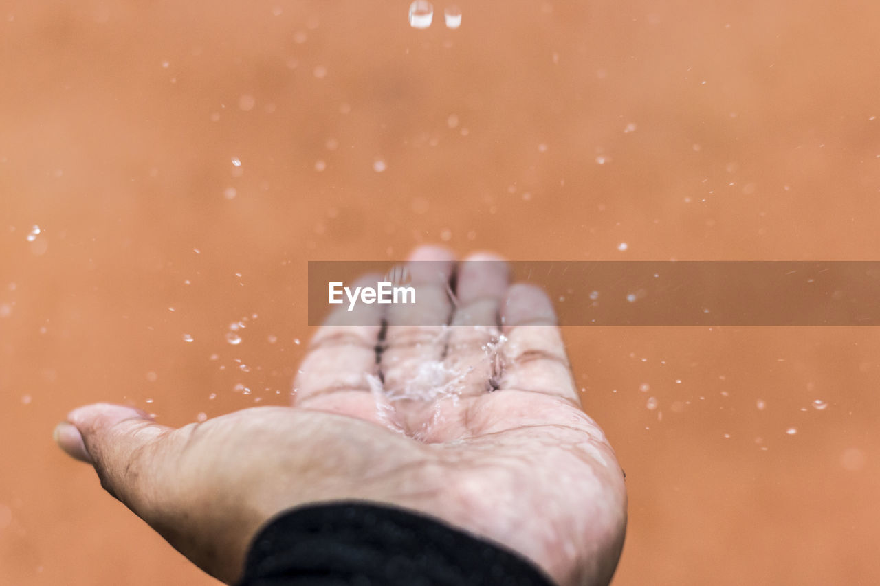 Close-up of water splashing on human palm