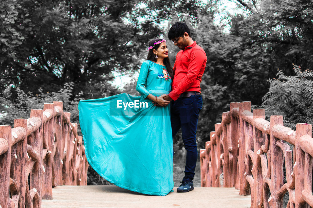 YOUNG COUPLE STANDING BY TREE