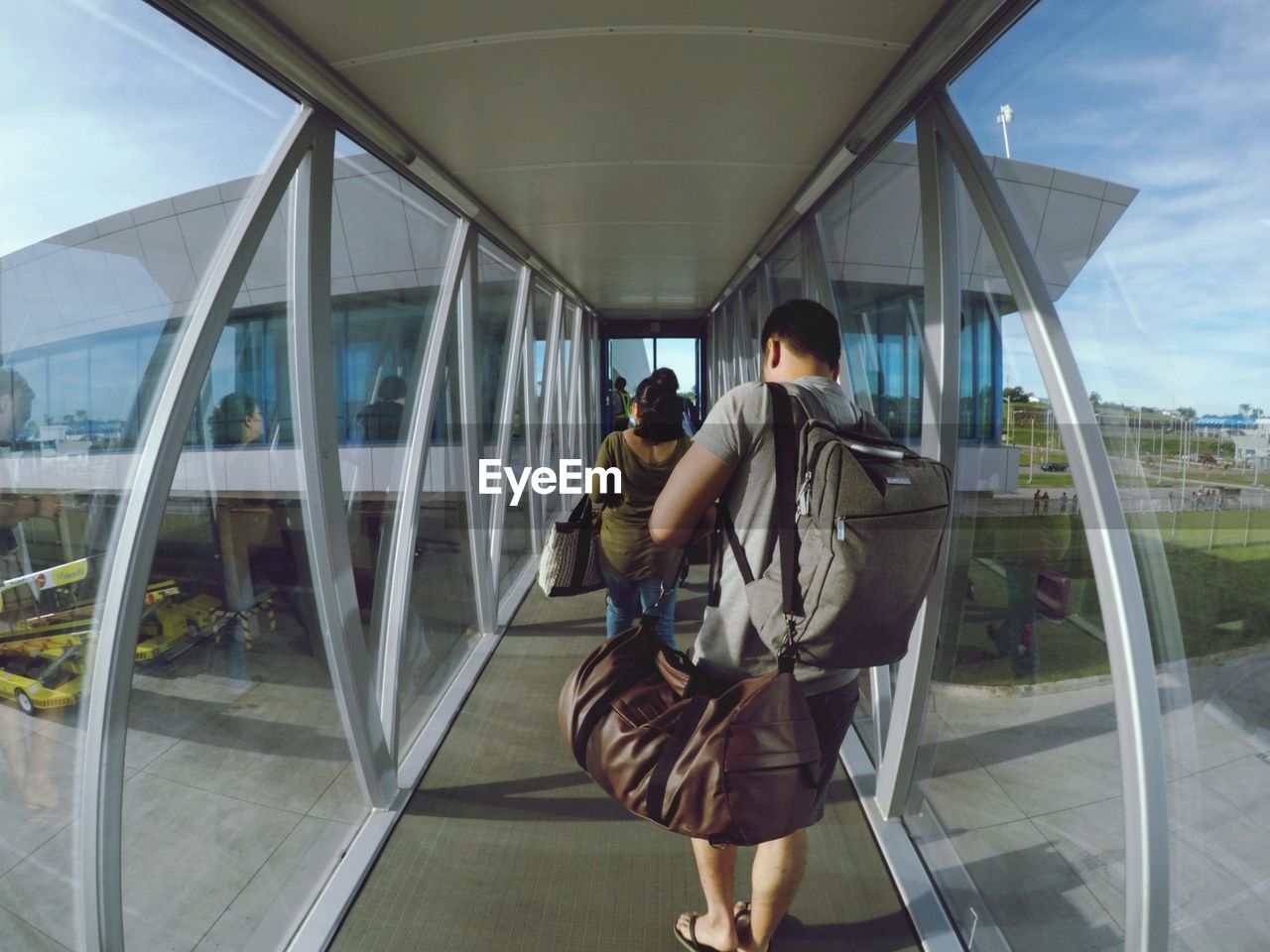 REAR VIEW OF PEOPLE WALKING IN GLASS BUILDING