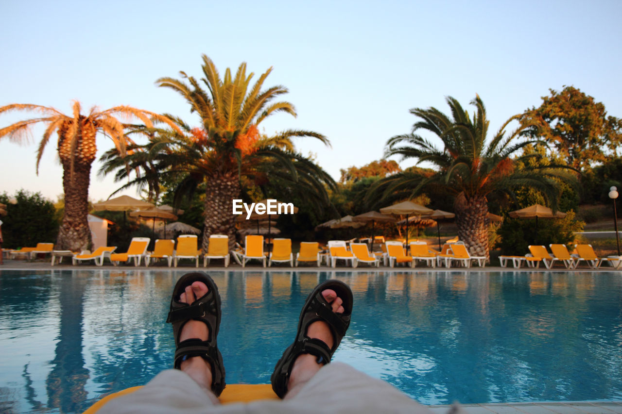 Low section of man in raft enjoying at swimming pool