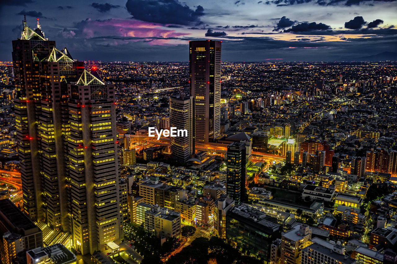 HIGH ANGLE VIEW OF ILLUMINATED BUILDINGS AGAINST SKY