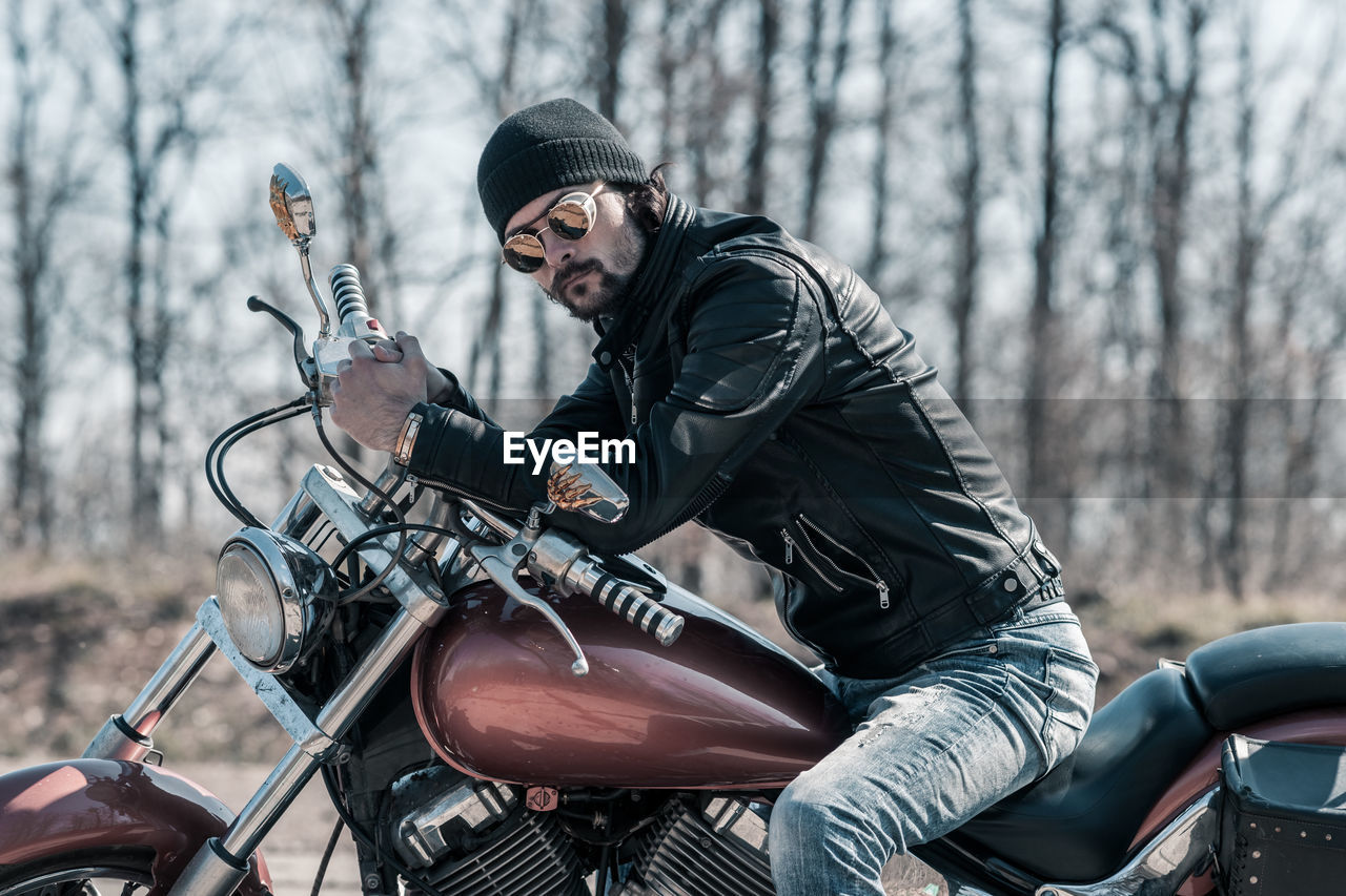 Mid adult man sitting on motorcycle in forest