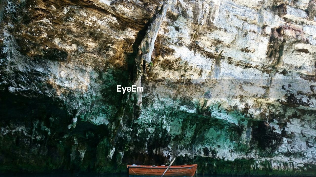 Row boat below rock formation