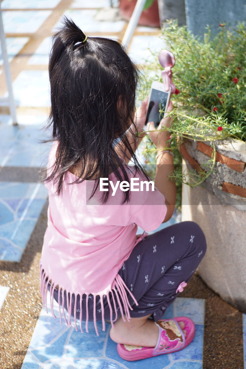 Close-up of girl taking picture of plants