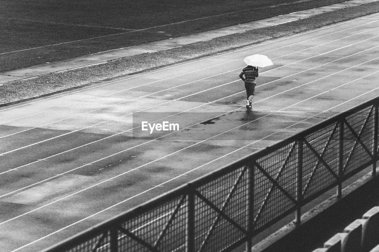 REAR VIEW OF MAN STANDING ON RAILING