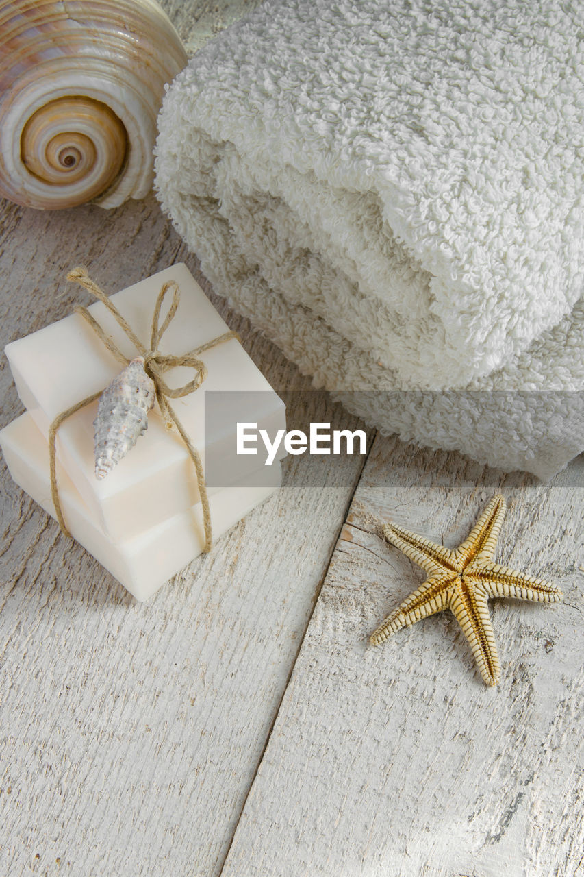 High angle view of soap bars with rolled up towel and starfish on wooden table