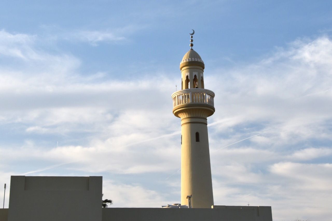 Low angle view of minaret against cloudy sky