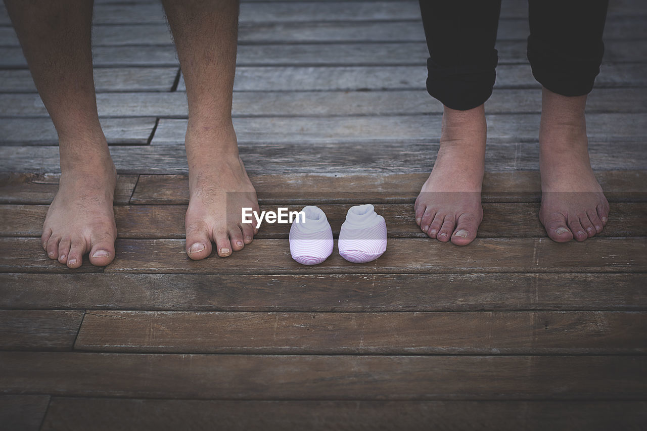 Low section of man and woman standing by baby shoes