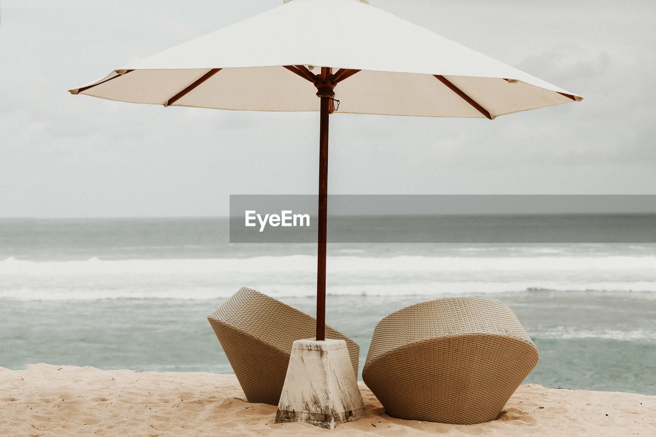 Deck chairs on beach against sky