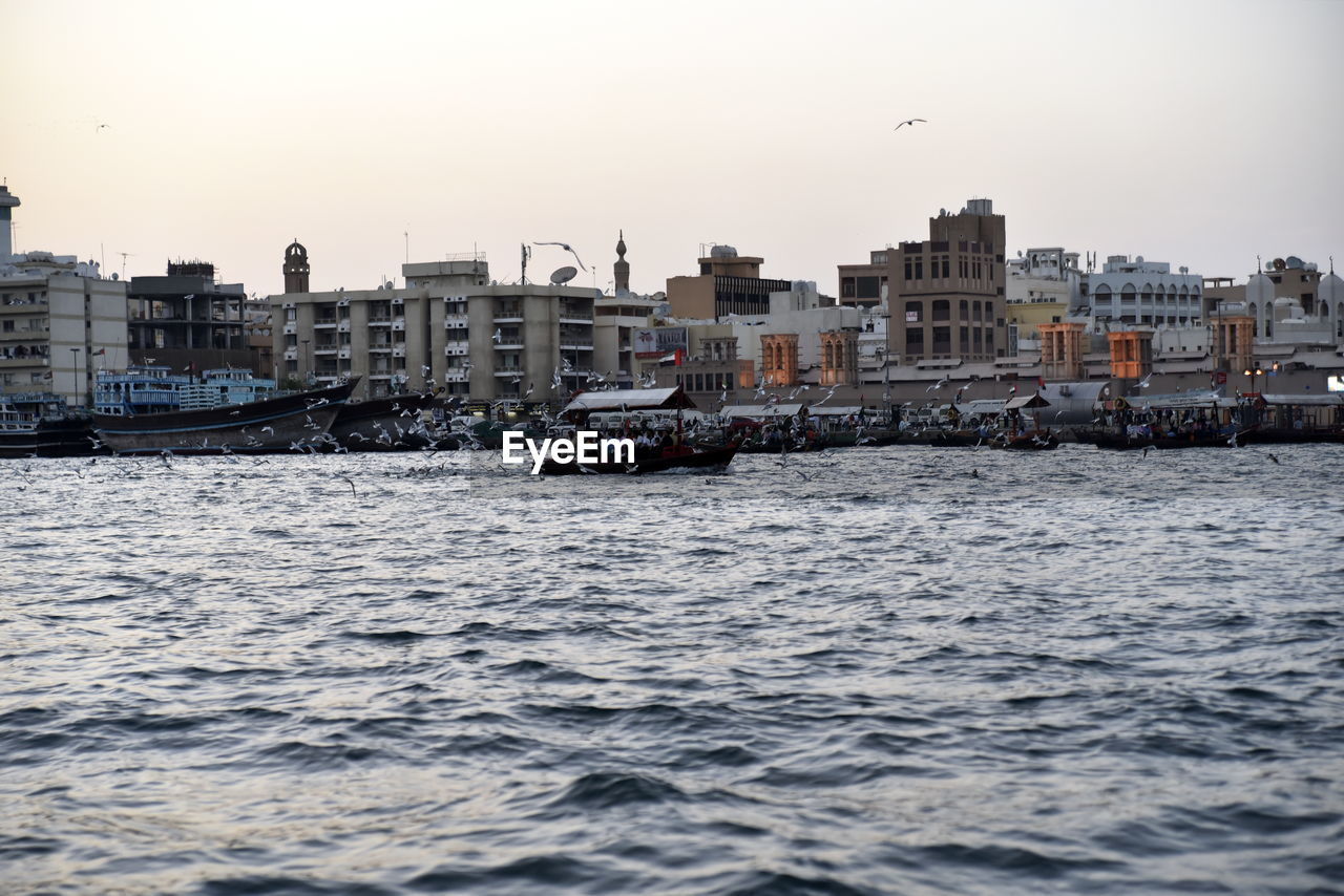 Buildings by sea against clear sky