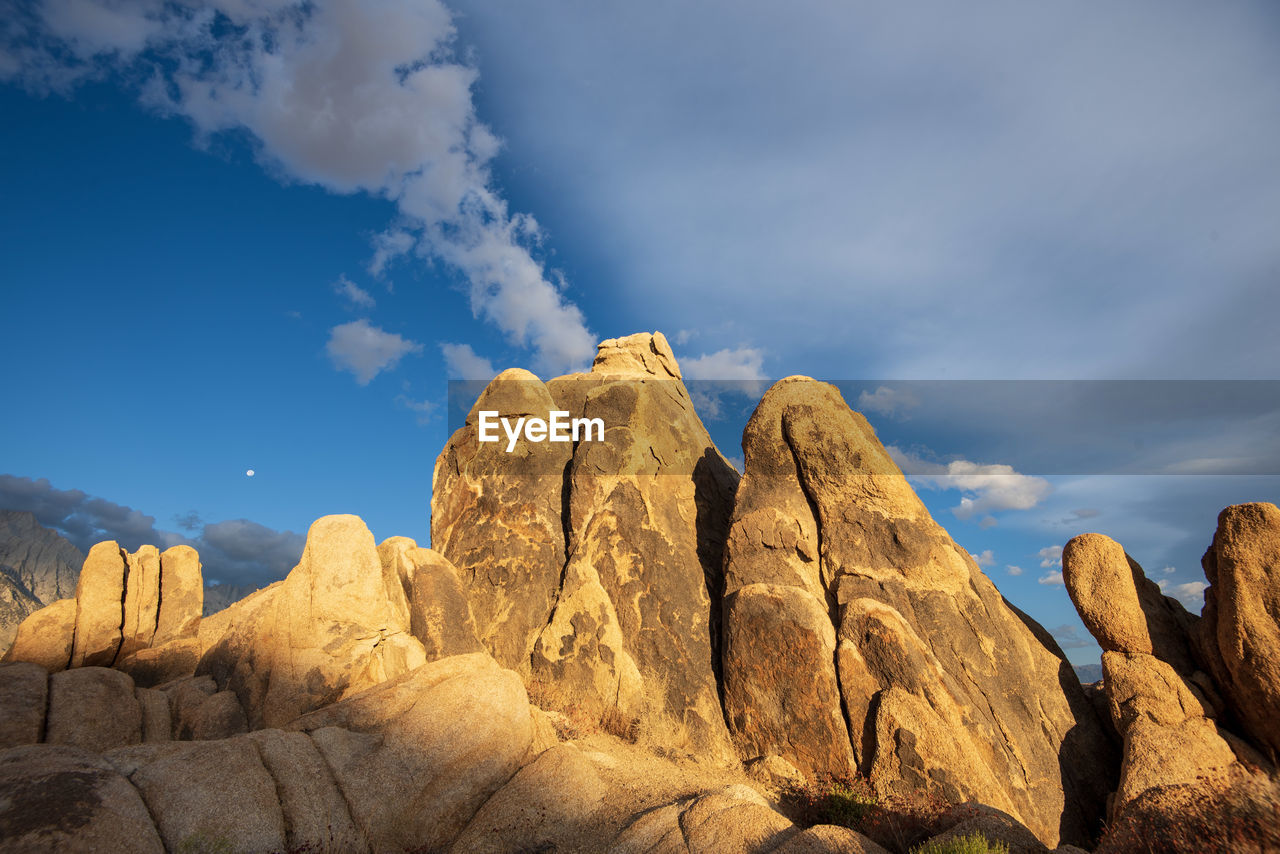 Morning sunshine on desert rock formations with white clouds in blue sky