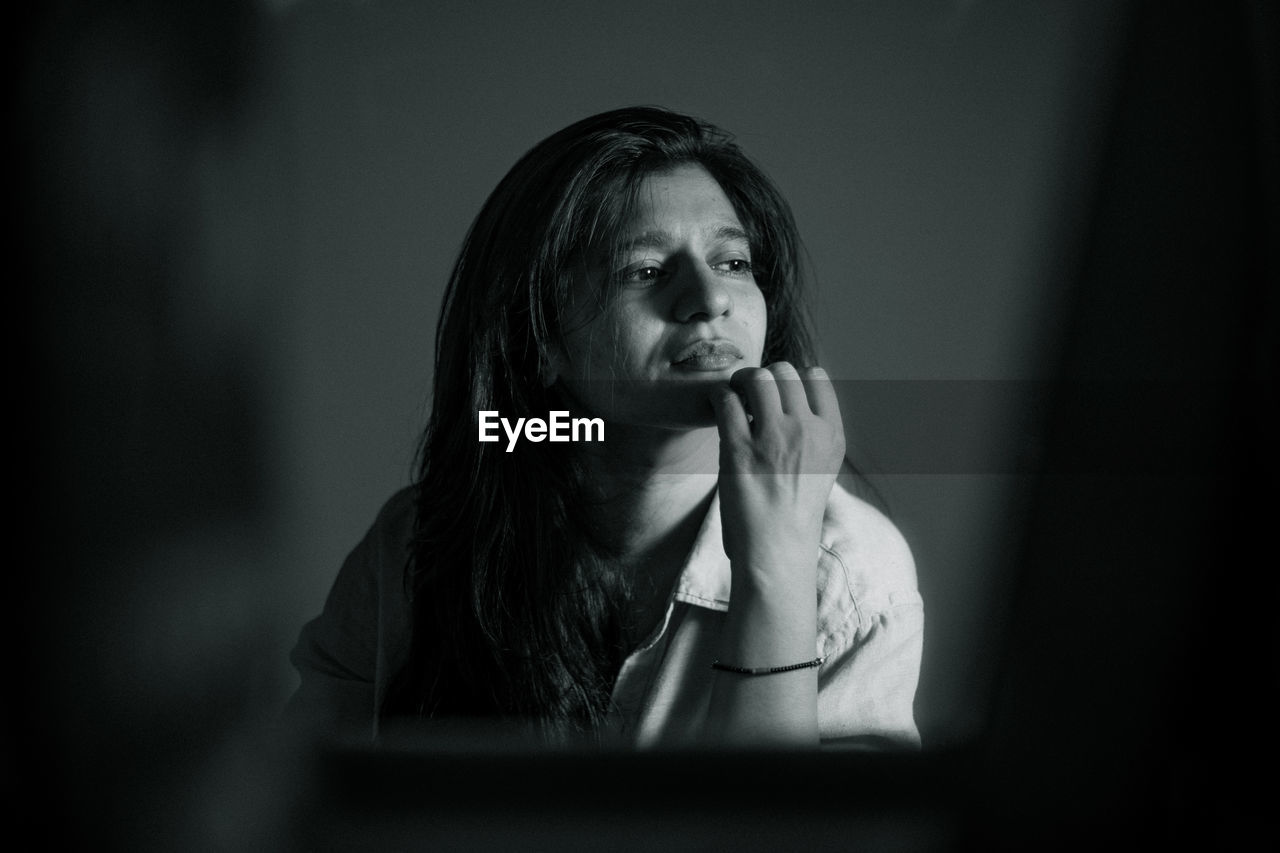 Close-up of woman looking away sitting in darkroom