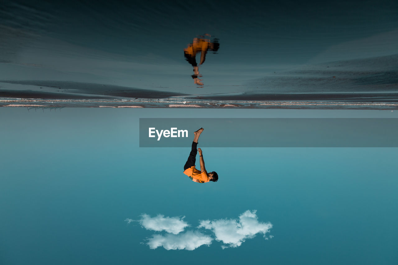 Low angle view of man jumping at sea against sky