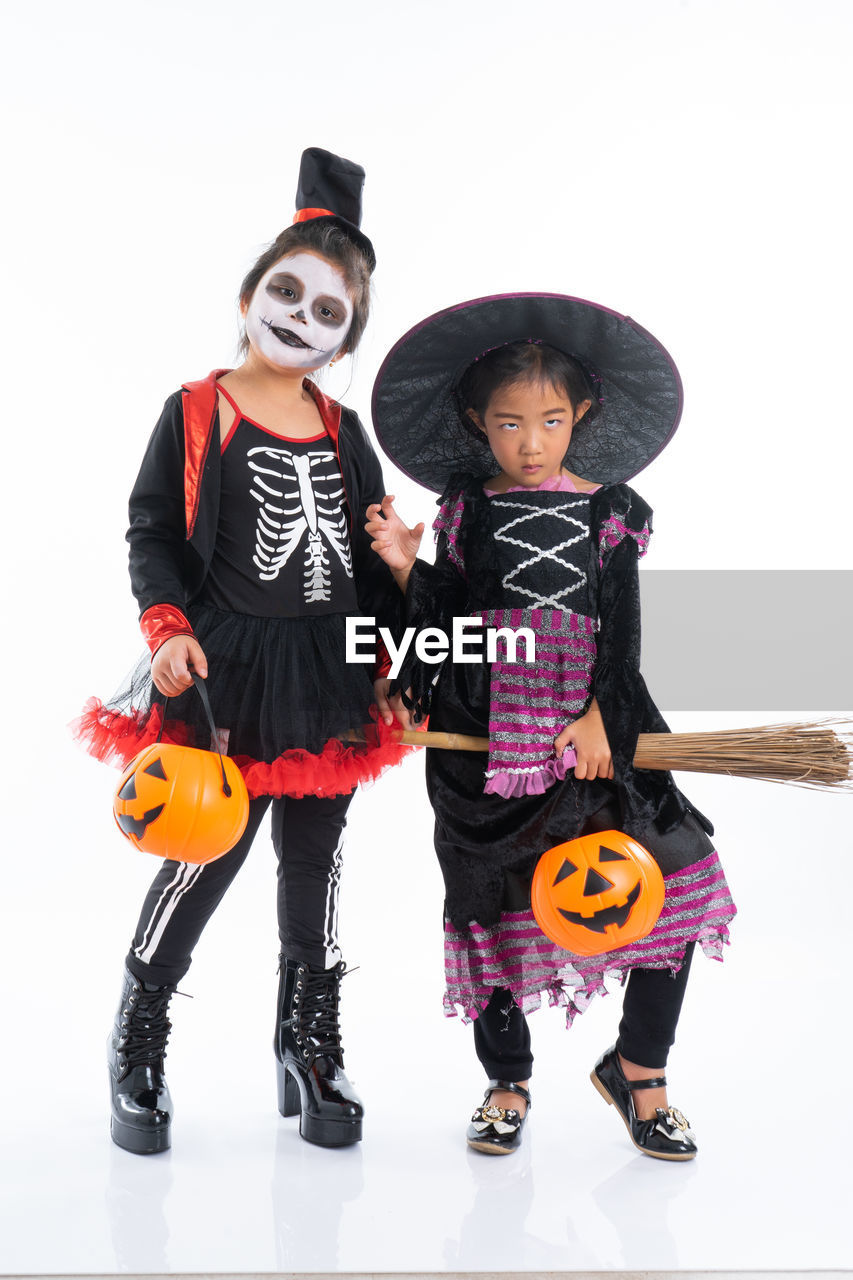 Portrait pair of little girls in halloween and carnival costume isolated on white background