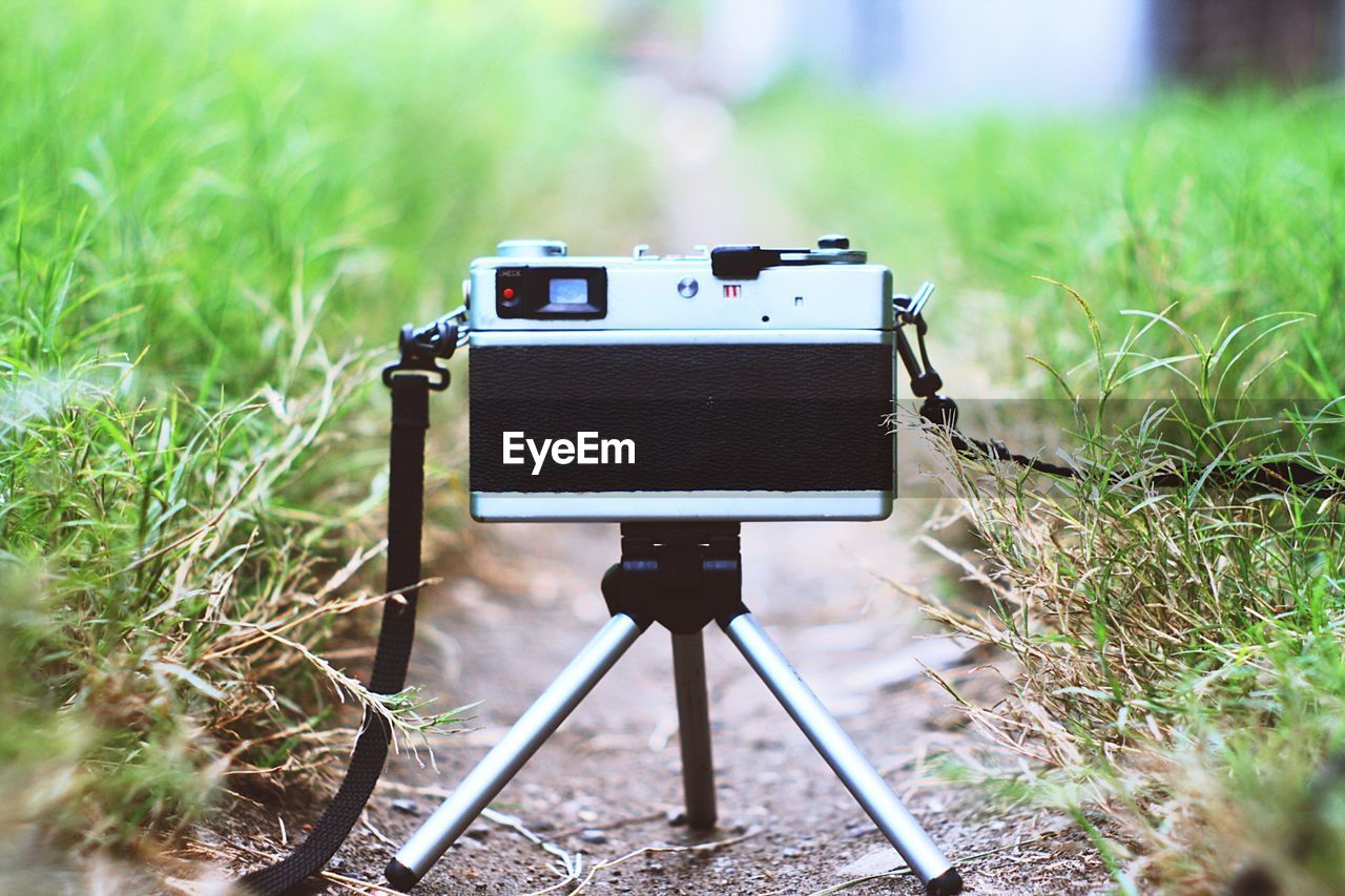 Close-up of camera on tripod amidst grass