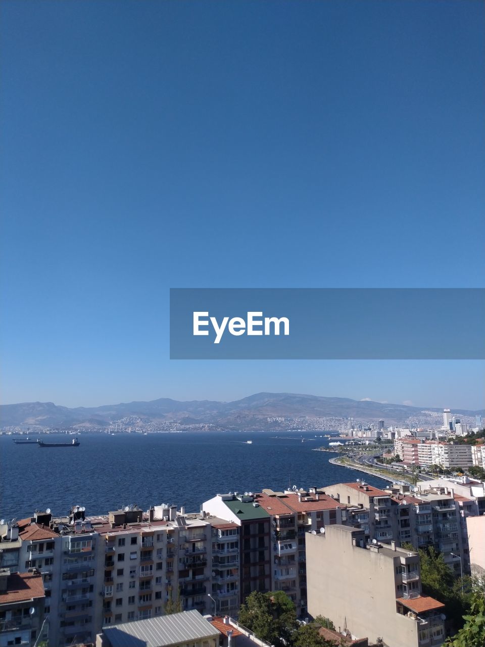 High angle view of city by sea against clear blue sky