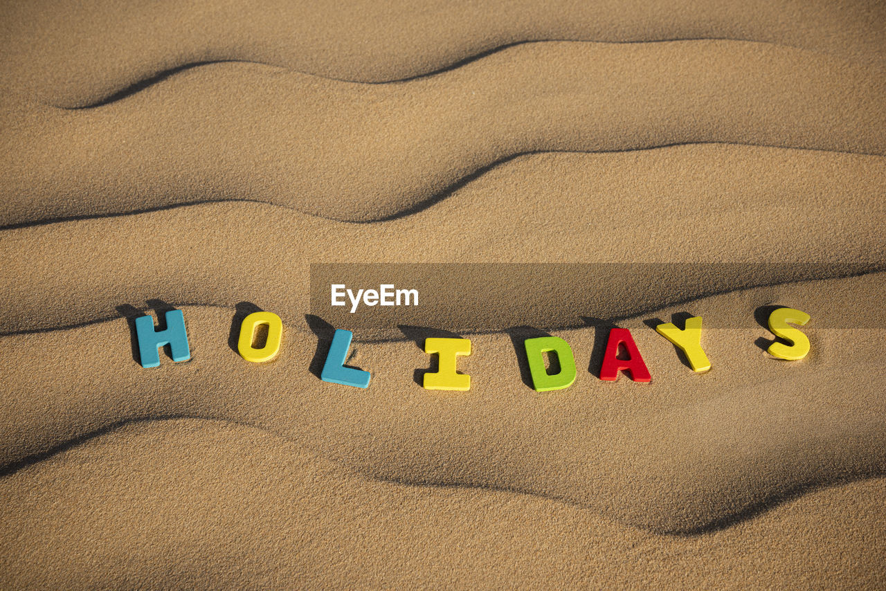 Holidays written out on wooden letters text on sand of a dune