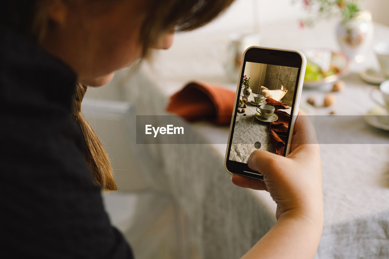 Video blog. a young woman is filming kitchen goods for her online store on her phone camera.