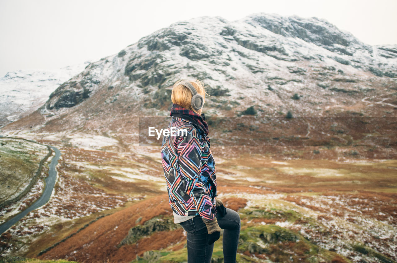 Young woman standing on cliff in mountains