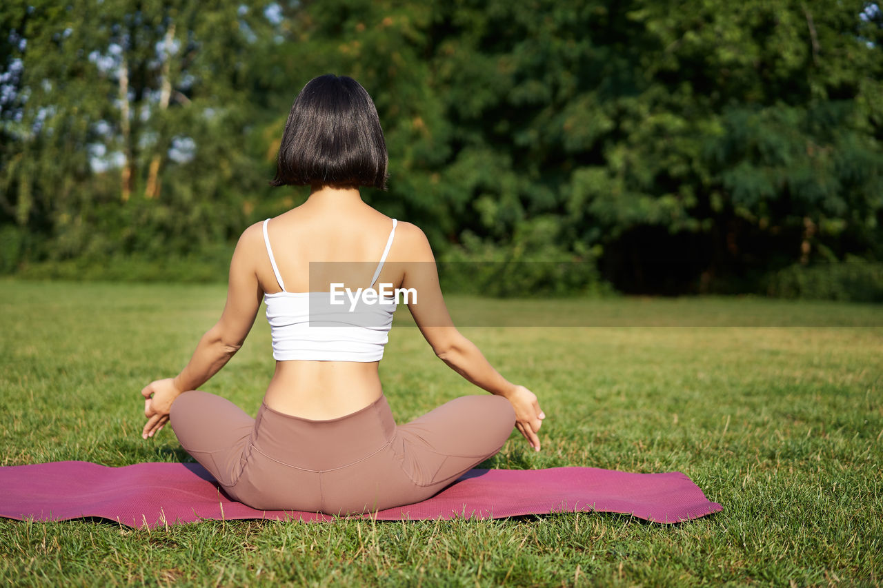 side view of young woman sitting on field