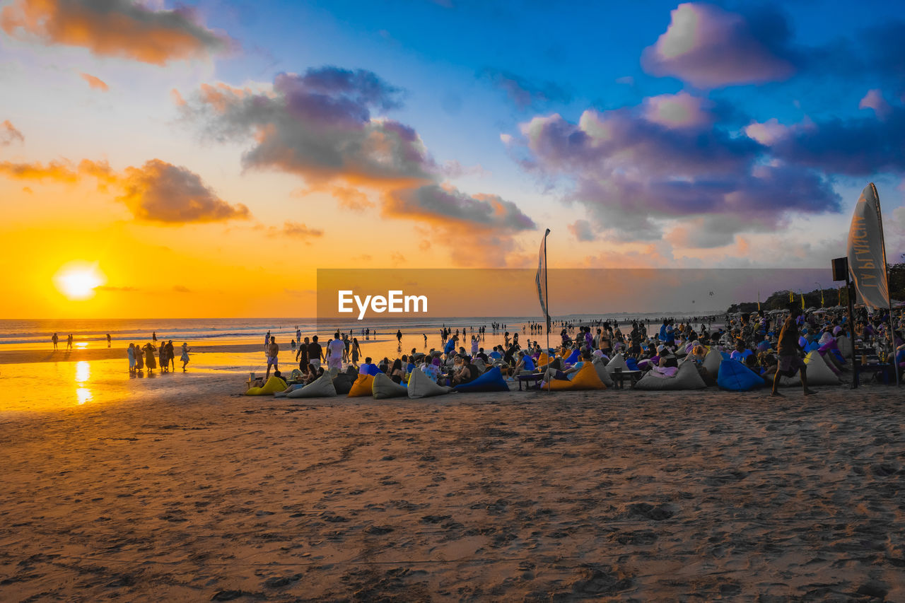 People at beach against sky during sunset