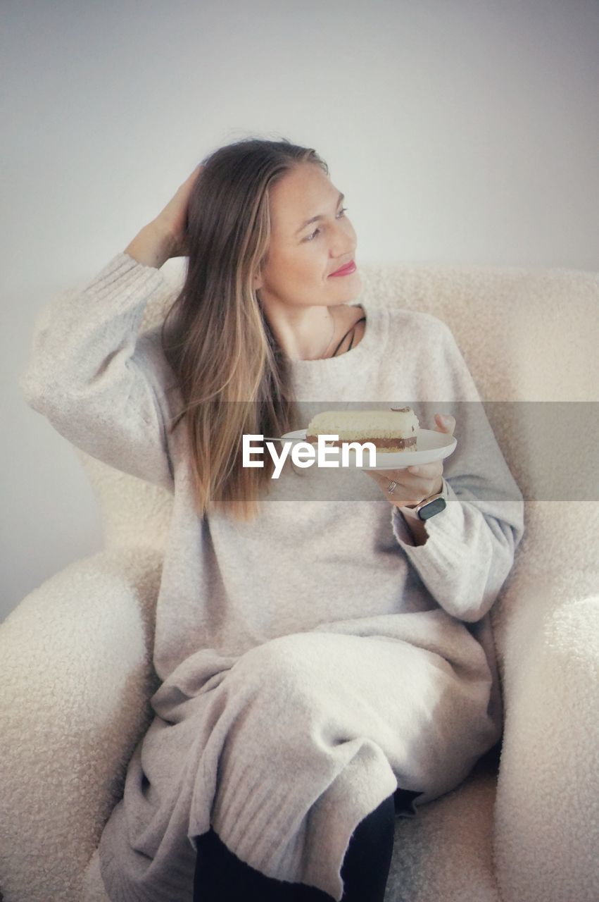 portrait of young woman using mobile phone while lying on sofa at home