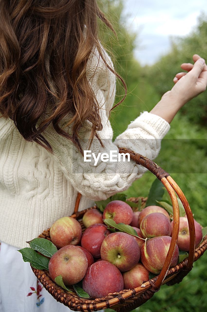 Midsection of woman holding app in basket