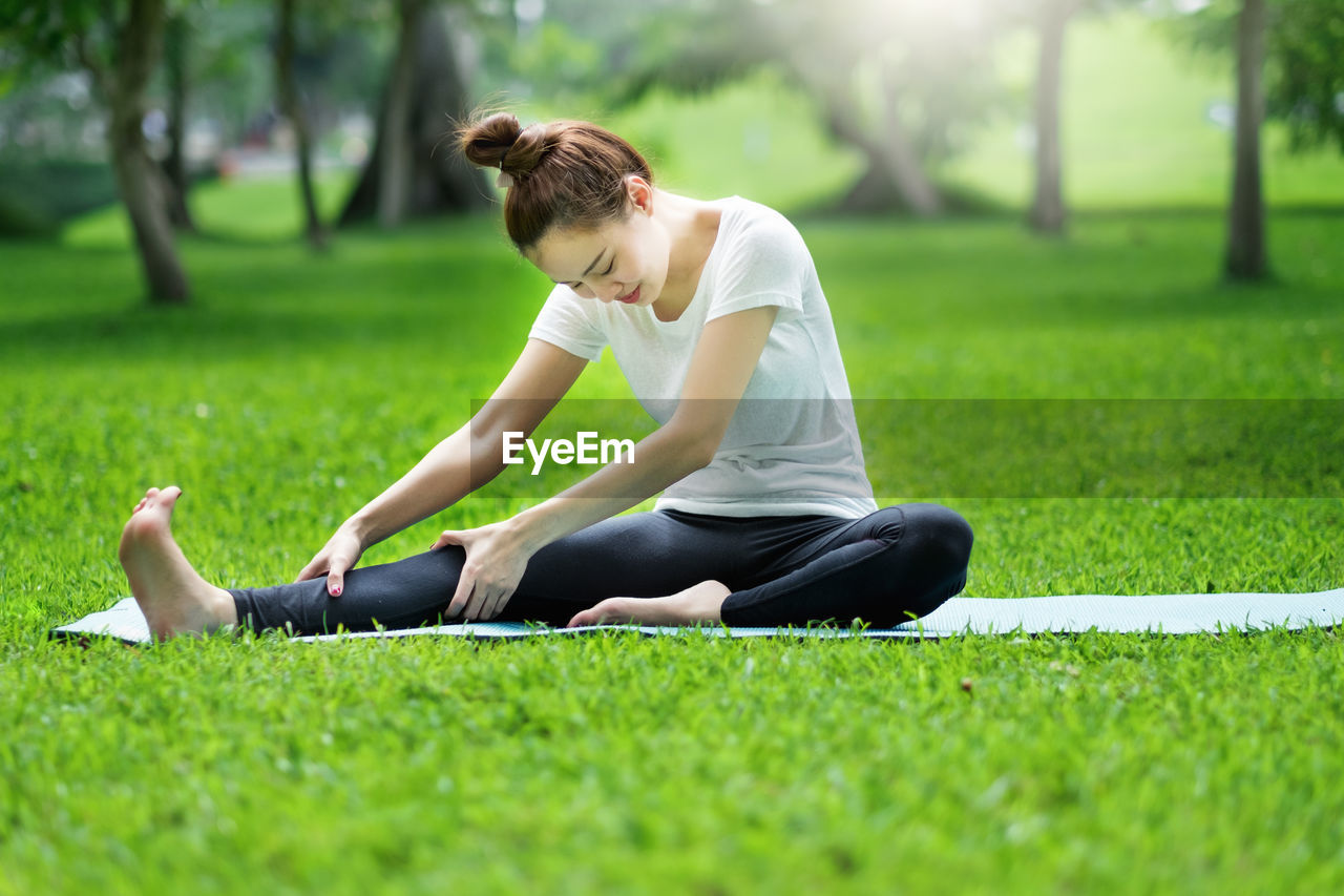 Woman stretching leg on field