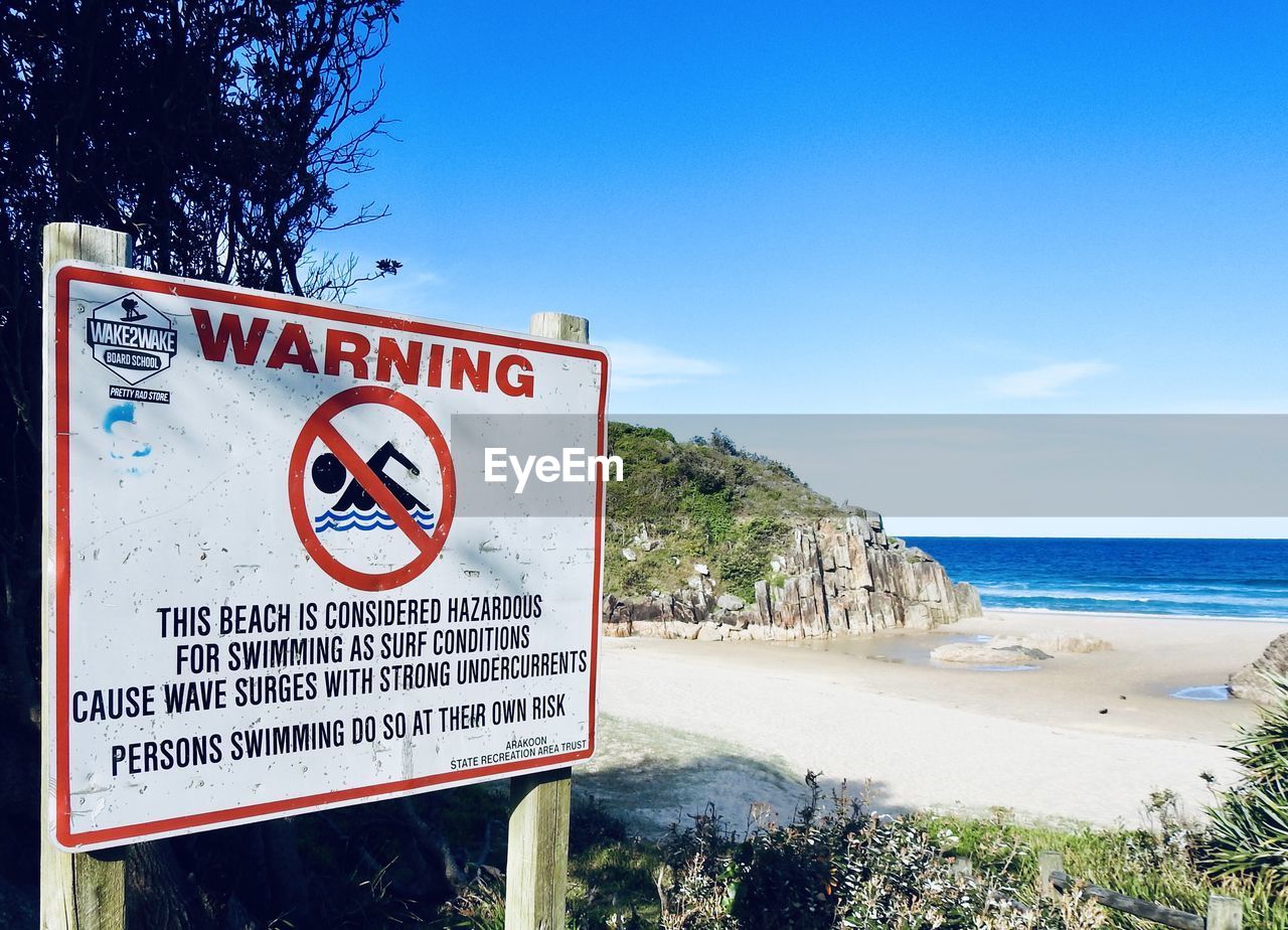 Information sign on beach against sky