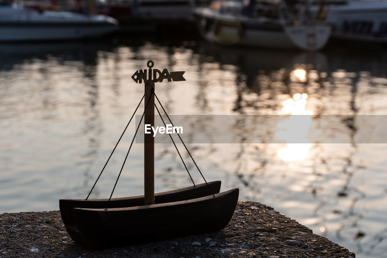 Wooden boat souvenir with red and light lighthouse, boat and tourists on background, nida, lithuania