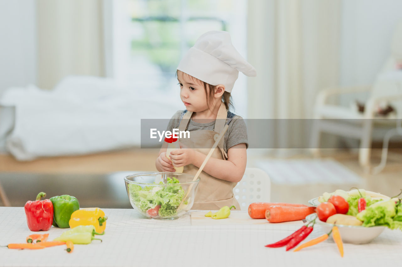 MIDSECTION OF GIRL HOLDING FOOD AT HOME