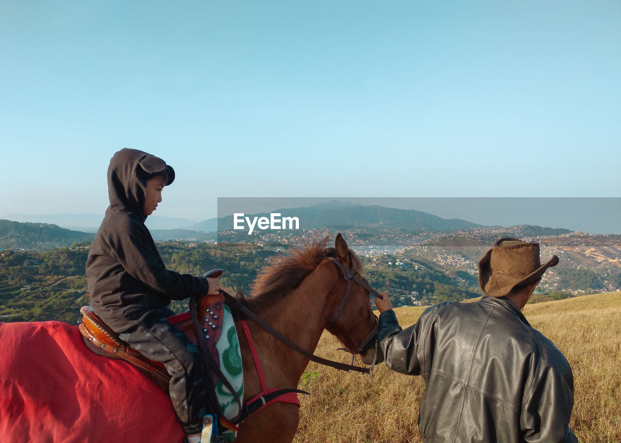 MAN RIDING HORSE IN A MOUNTAIN